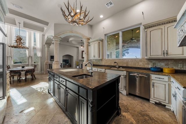 401 Brooks Hollow Rd, Lakeway, TX 78734 - kitchen with decorative columns, stainless steel dishwasher, a sink, cream cabinets, and arched walkways