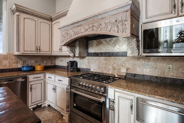 401 Brooks Hollow Rd, Lakeway, TX 78734 - kitchen with stainless steel appliances, tasteful backsplash, custom range hood, dark stone counters, and cream cabinets