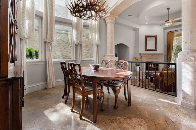 401 Brooks Hollow Rd, Lakeway, TX 78734 - dining area featuring decorative columns, arched walkways, a ceiling fan, a chandelier, and stone finish flooring