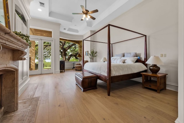 bedroom featuring a tray ceiling, access to outside, light wood-type flooring, french doors, and baseboards