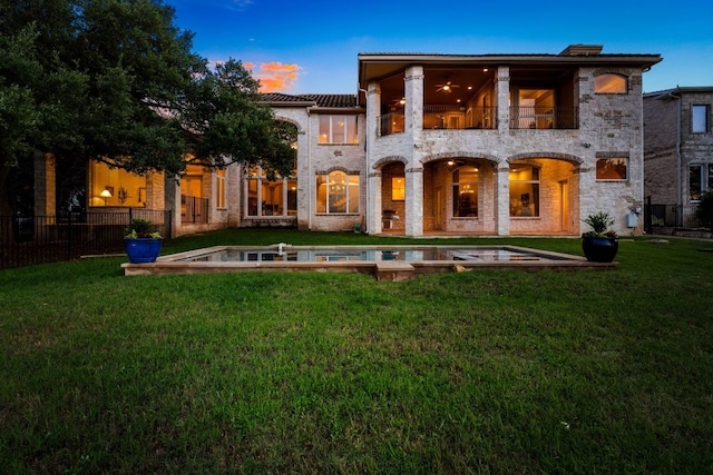 401 Brooks Hollow Rd, Lakeway, TX 78734 - back of house at dusk with a balcony, a tiled roof, and stone siding