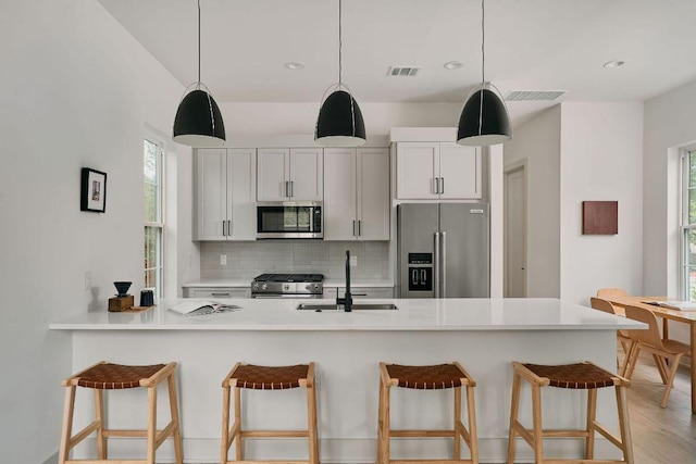 2209 Woodland Ave Unit 101, Austin, TX 78741 - kitchen with appliances with stainless steel finishes, a sink, backsplash, a breakfast bar, and hanging light fixtures