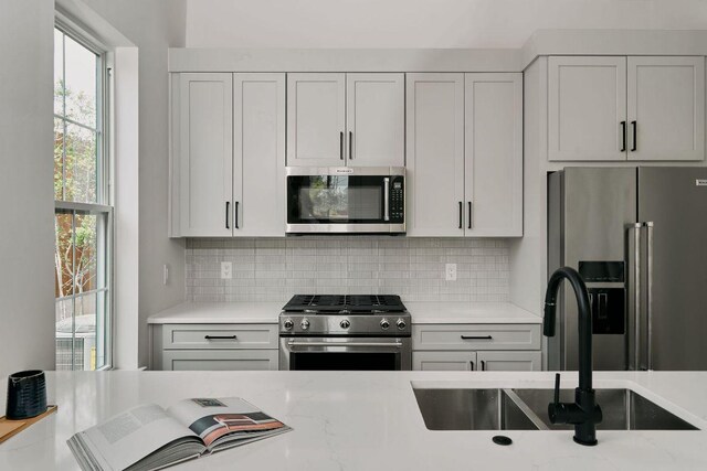 2209 Woodland Ave Unit 101, Austin, TX 78741 - kitchen featuring stainless steel appliances, a sink, decorative backsplash, and plenty of natural light