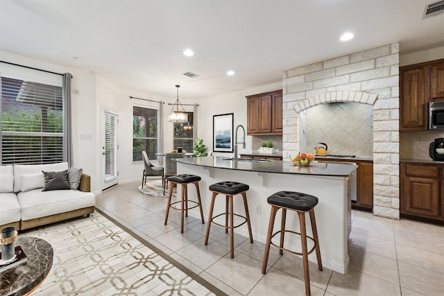199 Limestone Trl, Austin, TX 78737 - kitchen featuring stainless steel microwave, dark countertops, recessed lighting, light tile patterned floors, and a breakfast bar area