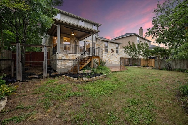 199 Limestone Trl, Austin, TX 78737 - back of house at dusk with a ceiling fan, a fenced backyard, stairs, and stone siding