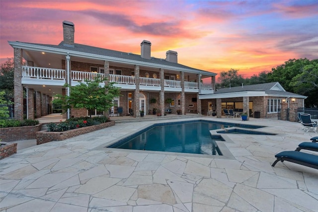 12 Hedge Ln, Austin, TX 78746 - rear view of property with a patio area, a balcony, a chimney, brick siding, and a pool with connected hot tub