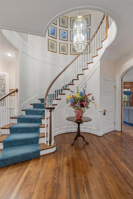 12 Hedge Ln, Austin, TX 78746 - staircase featuring arched walkways, wood finished floors, a chandelier, a decorative wall, and a towering ceiling