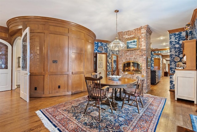 12 Hedge Ln, Austin, TX 78746 - dining area with a chandelier, a decorative wall, arched walkways, crown molding, and light wood-type flooring