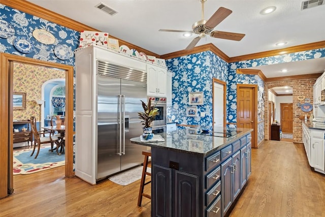 12 Hedge Ln, Austin, TX 78746 - kitchen with wallpapered walls, stainless steel appliances, arched walkways, crown molding, and white cabinets