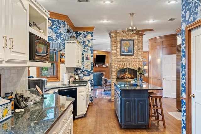 12 Hedge Ln, Austin, TX 78746 - kitchen with a ceiling fan, light wood finished floors, black appliances, a kitchen breakfast bar, and recessed lighting