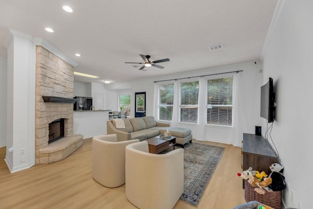 living room featuring a ceiling fan, light wood-type flooring, recessed lighting, and a fireplace