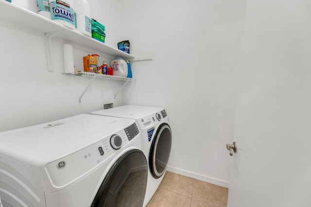 clothes washing area featuring separate washer and dryer, baseboards, and light tile patterned floors