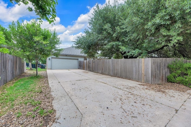 view of side of home with a garage, fence, and concrete driveway