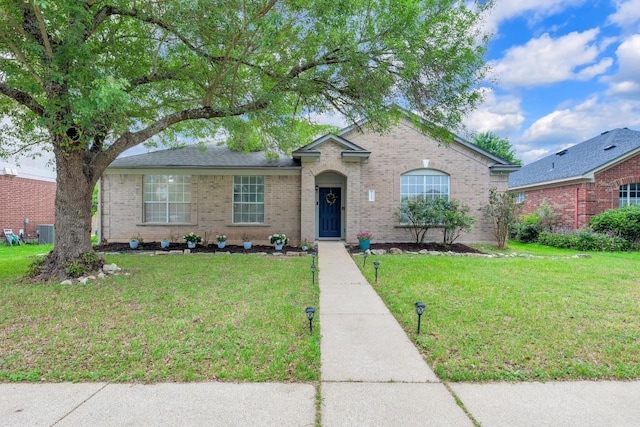 view of front of home with a front lawn, central AC unit, and brick siding