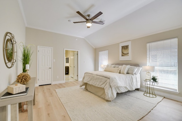 bedroom with crown molding, light wood-style floors, baseboards, vaulted ceiling, and ensuite bath