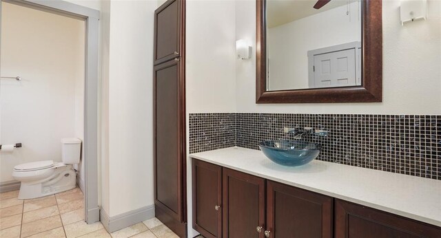 13918 Hummingbird Ln, Austin, TX 78732 - bathroom with vanity, toilet, decorative backsplash, baseboards, and tile patterned flooring
