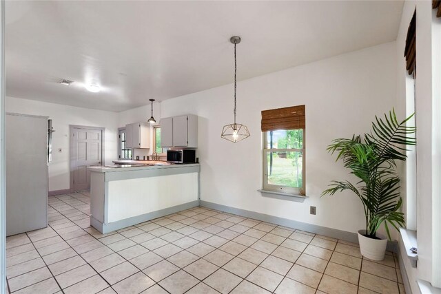 13918 Hummingbird Ln, Austin, TX 78732 - kitchen with a peninsula, stainless steel microwave, decorative light fixtures, and baseboards