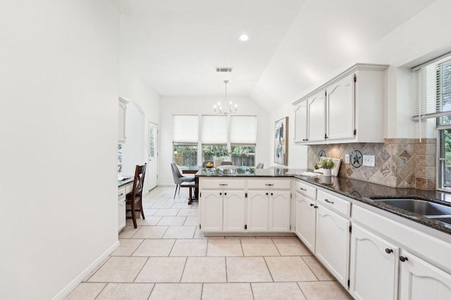 7403 Ponoma Trl, Austin, TX 78749 - kitchen featuring a peninsula, a chandelier, light tile patterned floors, tasteful backsplash, and lofted ceiling