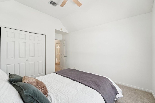 bedroom featuring lofted ceiling, light carpet, a closet, baseboards, and a ceiling fan