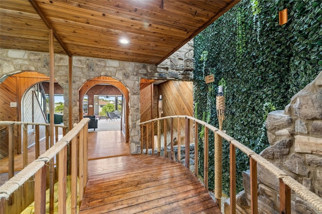 stairs with wooden ceiling, arched walkways, and wood finished floors