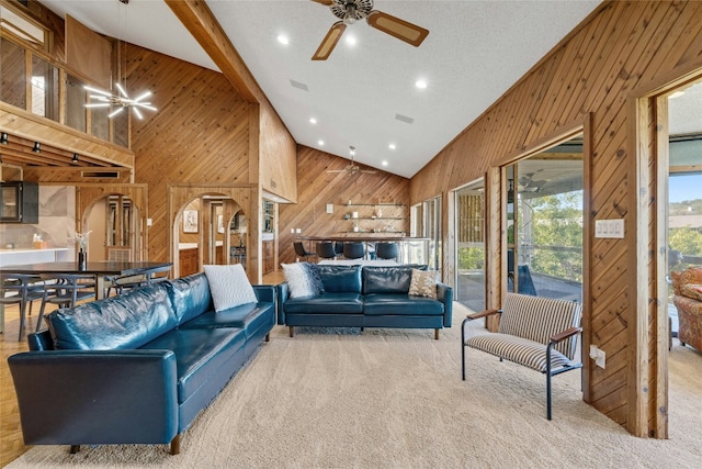 carpeted living room featuring wood walls, high vaulted ceiling, a ceiling fan, and recessed lighting