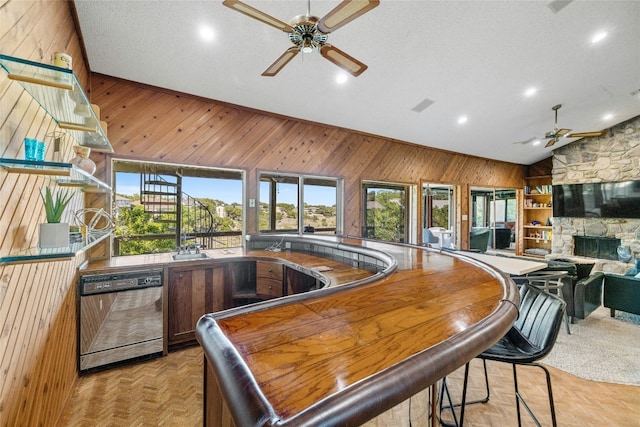 bar featuring ceiling fan, wooden walls, dishwasher, recessed lighting, and high vaulted ceiling