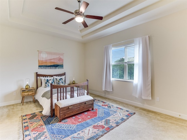 bedroom featuring a tray ceiling, carpet floors, and baseboards