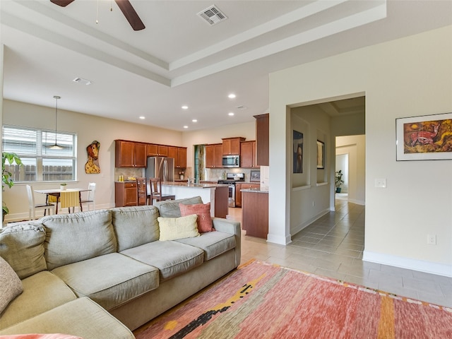 living room featuring light tile patterned flooring, a ceiling fan, recessed lighting, a tray ceiling, and baseboards
