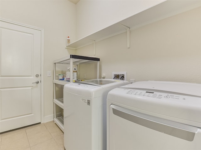 laundry area with independent washer and dryer and light tile patterned floors