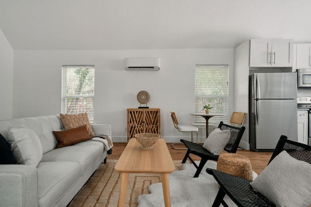 living area with an AC wall unit, light wood-style floors, and baseboards
