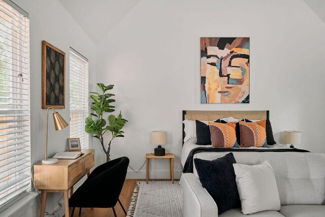 bedroom with wood finished floors and lofted ceiling