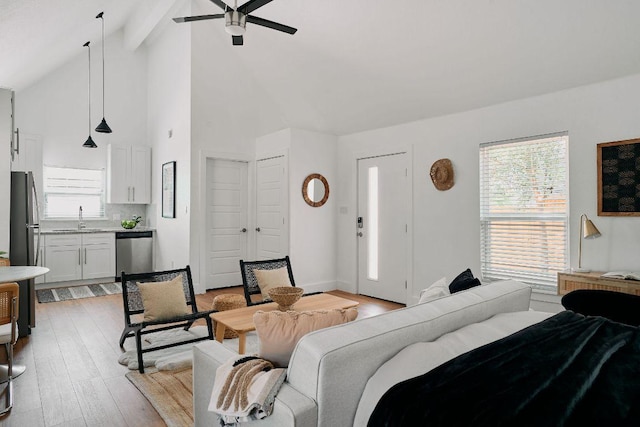 living room featuring a ceiling fan, beam ceiling, light wood finished floors, and high vaulted ceiling