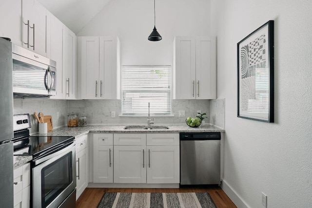kitchen with stainless steel appliances, a sink, backsplash, dark wood finished floors, and white cabinetry