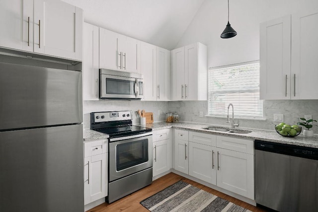 kitchen featuring stainless steel appliances, a sink, white cabinets, lofted ceiling, and light wood finished floors