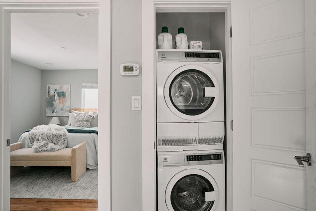 laundry area with stacked washing machine and dryer and wood finished floors