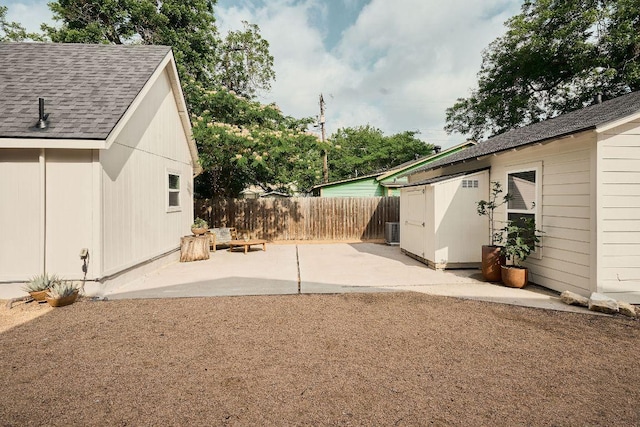 view of yard featuring a patio, fence, an outdoor structure, and central AC unit