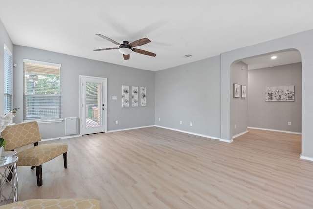 1180 Verna Brooks Way, Kyle, TX 78640 - unfurnished living room featuring arched walkways, ceiling fan, light wood-type flooring, and baseboards