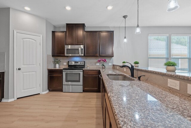 1180 Verna Brooks Way, Kyle, TX 78640 - kitchen featuring appliances with stainless steel finishes, a sink, light wood finished floors, decorative backsplash, and dark brown cabinetry