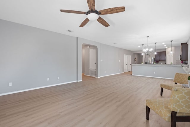 1180 Verna Brooks Way, Kyle, TX 78640 - living room with a ceiling fan, arched walkways, light wood finished floors, baseboards, and a chandelier