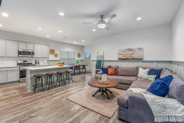 living room with light wood finished floors, recessed lighting, a ceiling fan, and wainscoting