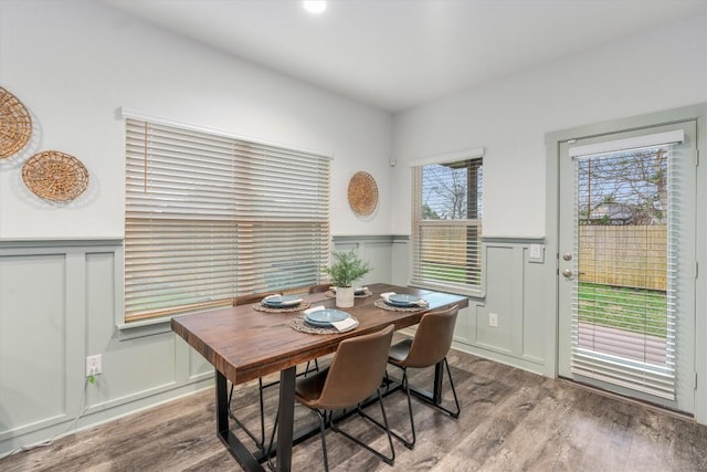 dining area featuring wood finished floors, a wainscoted wall, and a decorative wall