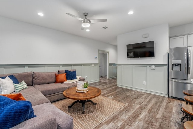 living area featuring light wood-type flooring, wainscoting, ceiling fan, recessed lighting, and a decorative wall