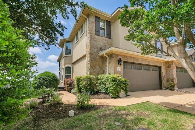 9617 Solana Vista Loop Unit A, Austin, TX 78750 - view of property with stone siding, a garage, stucco siding, and concrete driveway
