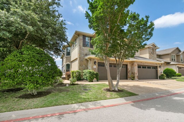 9617 Solana Vista Loop Unit A, Austin, TX 78750 - view of front of property with stone siding, concrete driveway, a front lawn, and a garage
