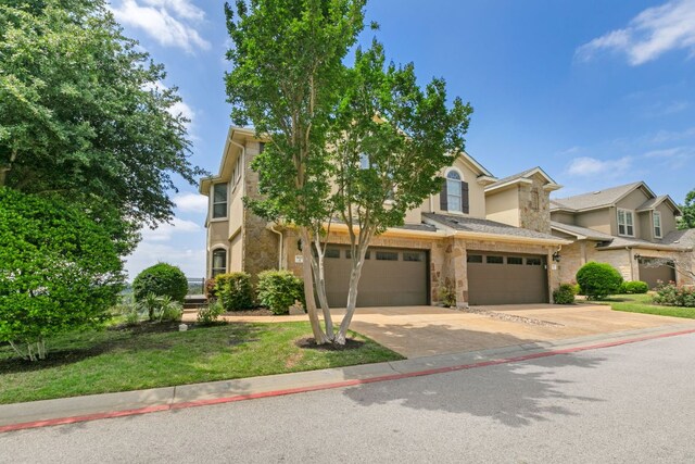 9617 Solana Vista Loop Unit A, Austin, TX 78750 - view of front of house with stone siding, an attached garage, driveway, and stucco siding