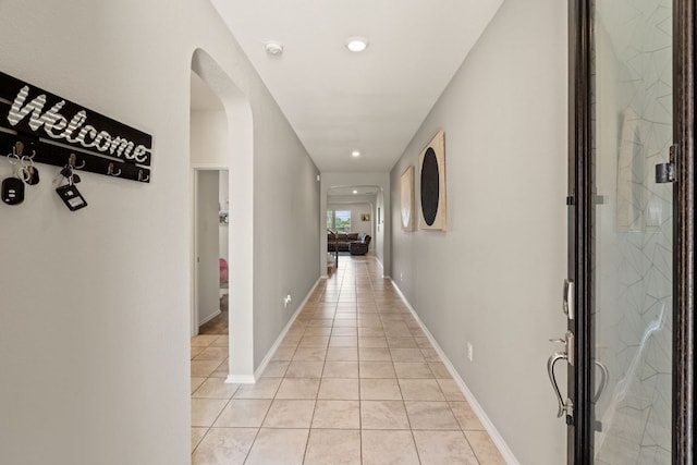 hall with arched walkways, light tile patterned floors, and recessed lighting