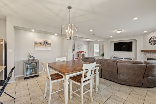 dining area featuring wine cooler, light tile patterned floors, a chandelier, recessed lighting, and a fireplace