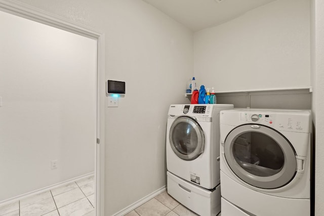 washroom with washing machine and clothes dryer, light tile patterned floors, and baseboards