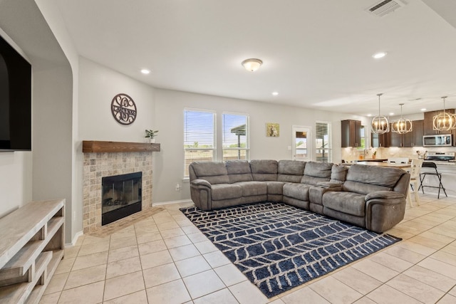 living room with light tile patterned floors, recessed lighting, a brick fireplace, and a chandelier