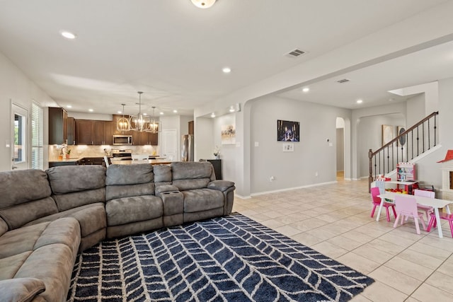 living room featuring light tile patterned floors, arched walkways, recessed lighting, a chandelier, and stairway